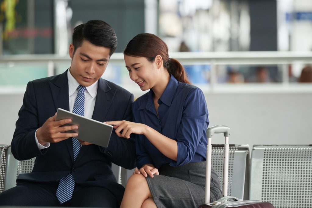 Asian Couple Using Tablet in Airport - Oasis Credit Money Management Tips