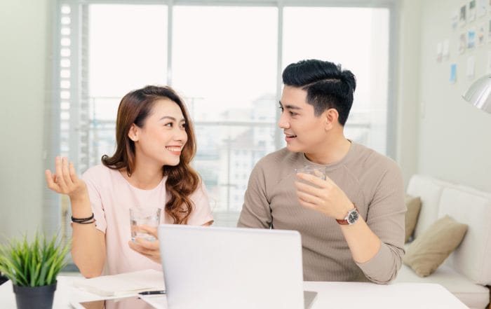 cheerful young male and female laughing while making plans for family budget communicating - Oasis Credit
